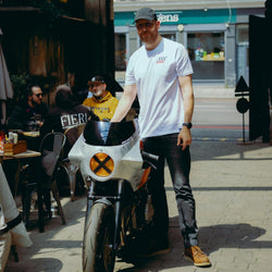 Model wearing Bike Shed Motorcycle Race T-Shirt White next to a custom motorcycle.