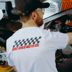 Model wearing Bike Shed Motorcycle Race T-Shirt White next to a custom motorcycle.