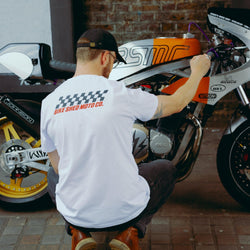 Model wearing Bike Shed Motorcycle Race T-Shirt White next to a custom motorcycle.