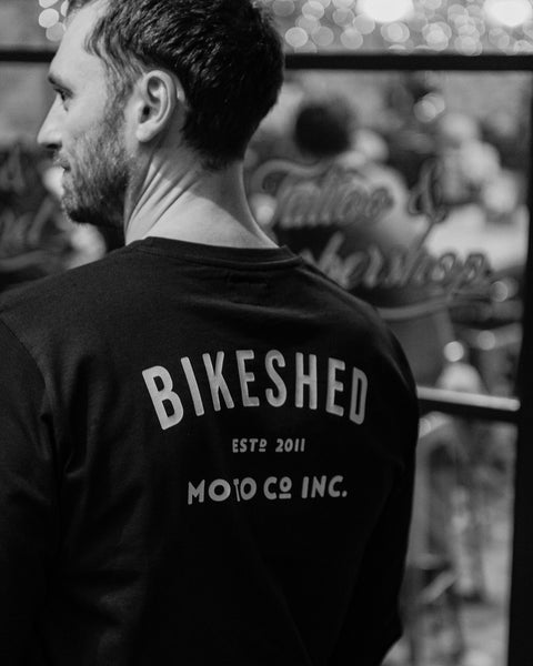 Model wearing Bike Shed Moto Co ESTD Black Longsleeve in the Bike Shed London Restaurant 