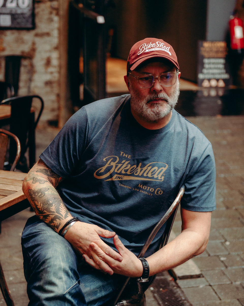 Model wearing Bike Shed Moto Co Inc T-Shirt Blue on brick driveway