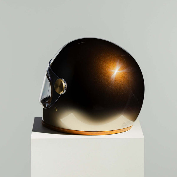 Helmet with a gradient finish on a white pedestal against a gray background